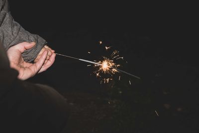 Cropped hands of people holding sparkler at night