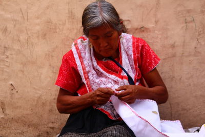 Mid adult woman holding red while sitting outdoors