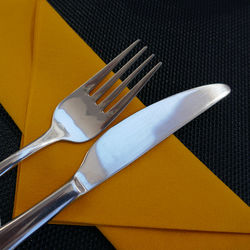 High angle view of fork and table knife on tissue papers at table