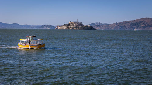 Boat sailing on sea against clear sky