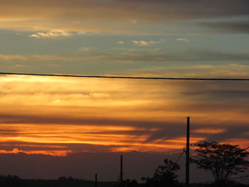 Low angle view of silhouette trees against dramatic sky