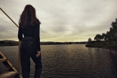 Rear view of woman standing against lake