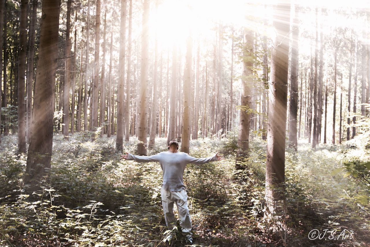 REAR VIEW OF MAN STANDING WITH ARMS OUTSTRETCHED