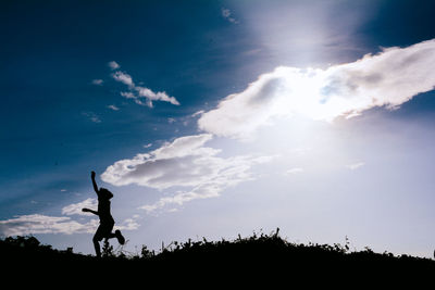 Low angle view of silhouette man against blue sky