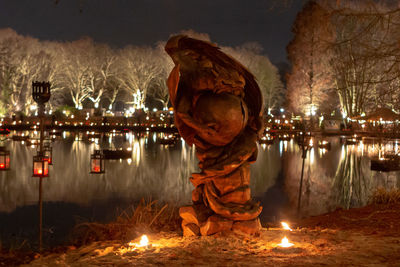 Panoramic shot of illuminated statue by lake at night