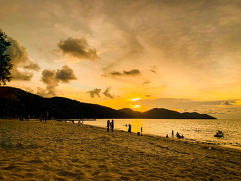 Silhouette people on beach against sky during sunset