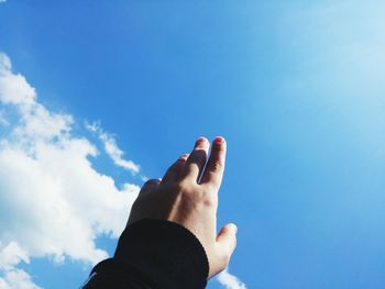 Low angle view of hand against blue sky