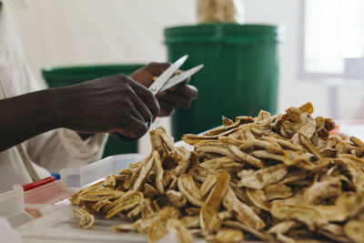 Midsection of man cutting dried bananas
