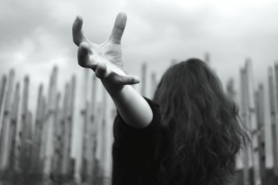 Rear view of woman with arms raised standing against blurred background