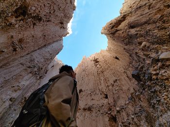 Rear view of man on rock formation against sky