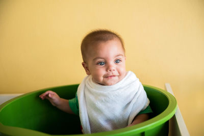 Close-up cute smiling baby boy sitting in bucket at home