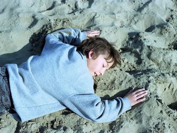 High angle view of boy lying on sand at beach