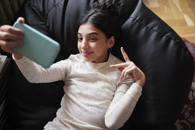 Girl lying on bean bag and taking selfie