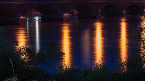 Arch bridge over river at night