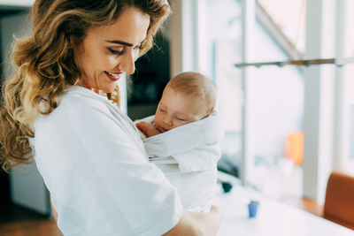 Mother carrying newborn son at home