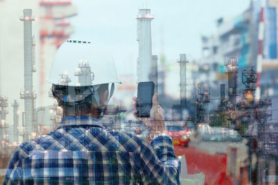 Rear view of man using mobile phone in city