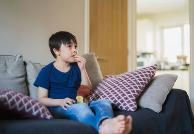 Boy sitting on sofa at home