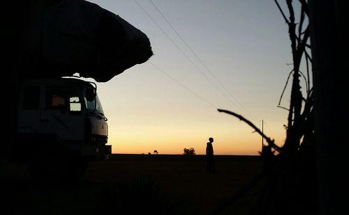 Silhouette of electricity pylon against sky during sunset