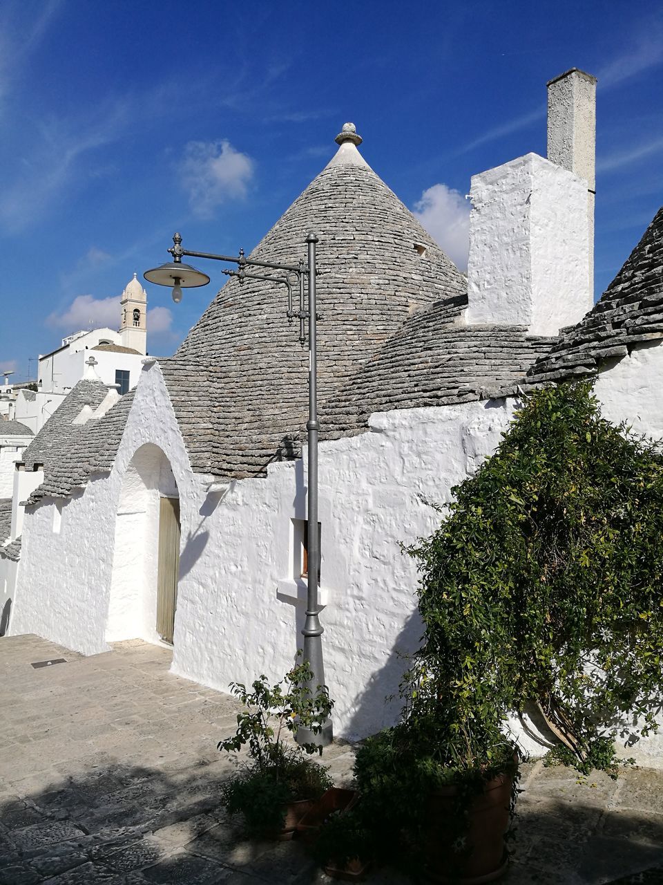 religion, spirituality, architecture, place of worship, day, built structure, history, cross, building exterior, outdoors, low angle view, no people, travel destinations, sky, whitewashed, tree, ancient civilization, nature