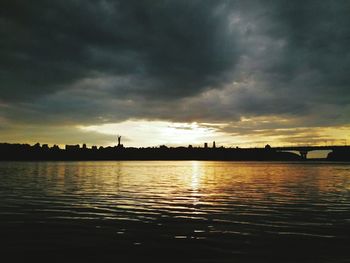 Scenic view of lake against dramatic sky during sunset