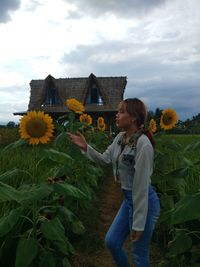 Woman looking at sunflower while standing outdoors