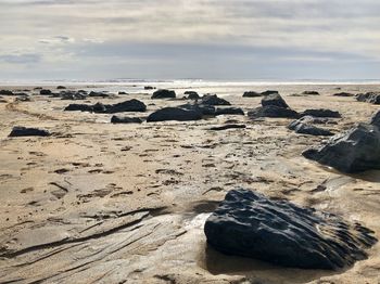 Scenic view of rocks on beach against sky