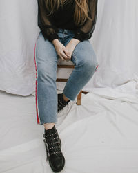 Low section of woman stool against curtain