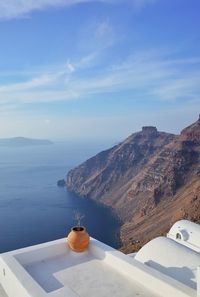 Scenic view of mountains by sea against blue sky seen from building terrace