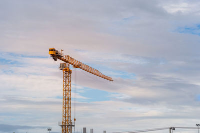 Tower crane on blue sky with clouds.