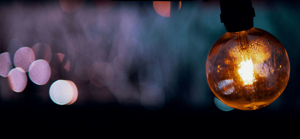 Close-up of illuminated light bulb against blurred background