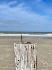Wooden posts on beach against sky