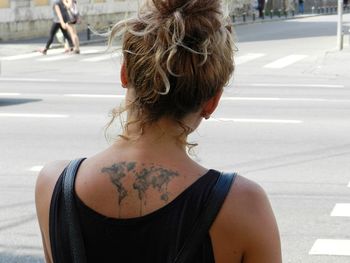 Rear view of woman with world map tattoo on back