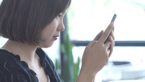 Close-up portrait of young woman using mobile phone