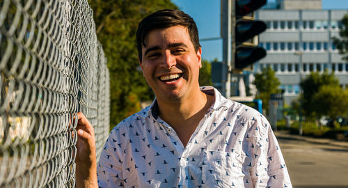 Portrait of man standing by chainlink fence