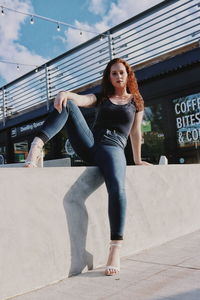 Portrait of smiling young woman standing against built structure