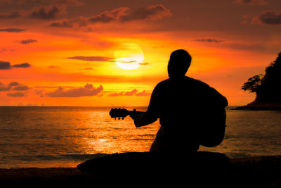 Silhouette man on beach against sky during sunset