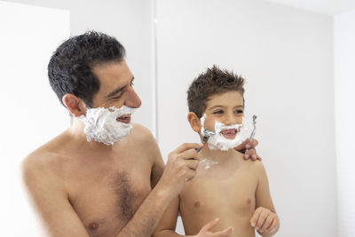 Funny father and son shaving in the bathroom