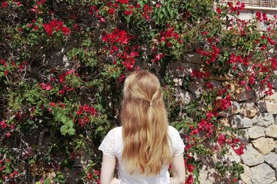 Rear view of woman standing by flowering plants