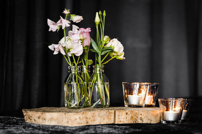 Flower vase with lit tea light candles on table