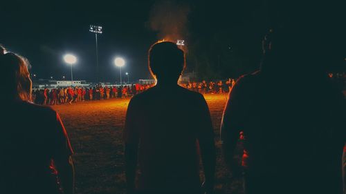 Rear view of people standing at night