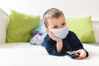 Portrait of boy sitting on bed at home