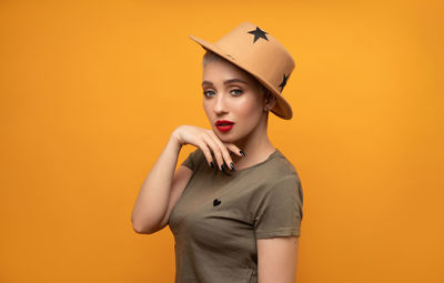 Portrait of beautiful young woman against yellow background