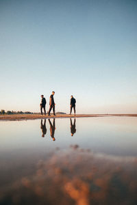 Silhouette people on water against clear sky