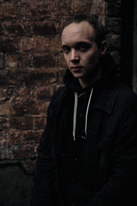 Portrait of young man standing against wall