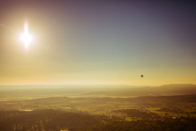 Hot air balloon flying over landscape against sky during sunset