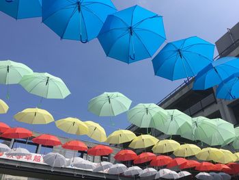 Low angle view of multi colored umbrellas against blue sky