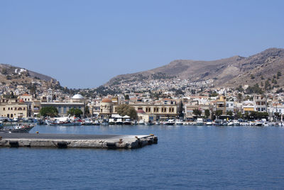 Aerial view of townscape by sea against clear blue sky