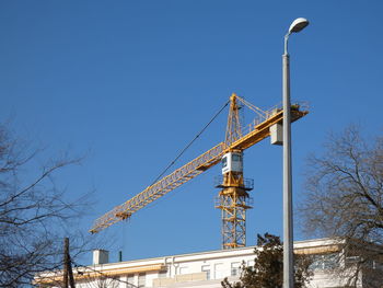 Low angle view of crane against clear blue sky