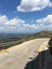 Road leading towards city against sky