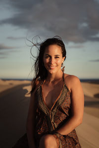 Portrait of smiling woman on beach against sky during sunset